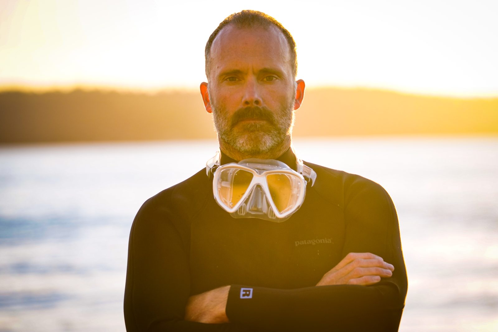 Gabe Newton in a wetsuit and dive mask at sunset.